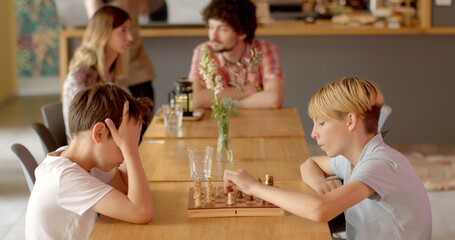 Obraz na płótnie Canvas Children in cafe playing chess stands as timeless example of tabletop game that offers exceptional alternative to gadgets and screen time for children in urban environments. Face-to-face interactions.