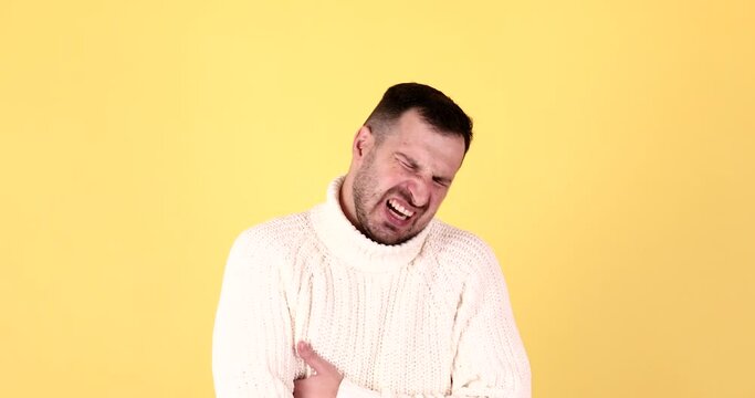Bearded guy feeling sudden stomach pain, severe abdominal distress, suffering constipation, gastritis, pancreatic diseases. Studio shot isolated on yellow background.