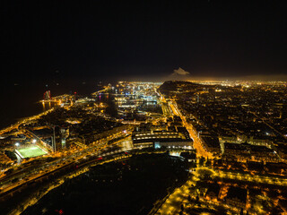 Breath taking aerial view of night city. Illuminated streets in coastal urban borough and marina. Barcelona, Spain