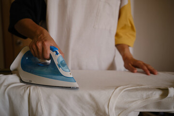 wuman ironing white clothes on the ironing board. Ironing process. Housewife ironing clothes