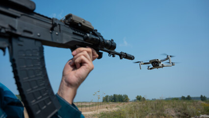 Man aiming to shoot a rifle at a flying drone outdoors. 