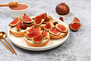 Healthy breakfast with ingredients, toast with figs and soft cream cheese ricotta and honey, canapes or crostini with toasted baguette and herbs on gray concrete table, Italian recipe menu,