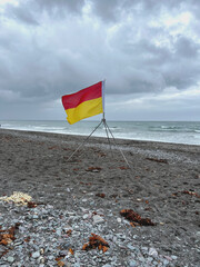 Flagge rot gelb begrenzte Badezone am stürmischen Meer 
