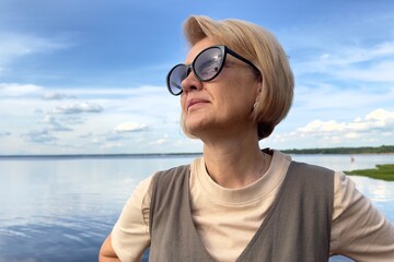 Portrait of happy beautiful elderly senior woman in sunglasses enjoy summer sunny day at beach, sea 