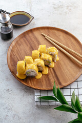 Sushi and soy sauce in a bowl and wooden chopsticks on a gray wooden table. Japanese food. 