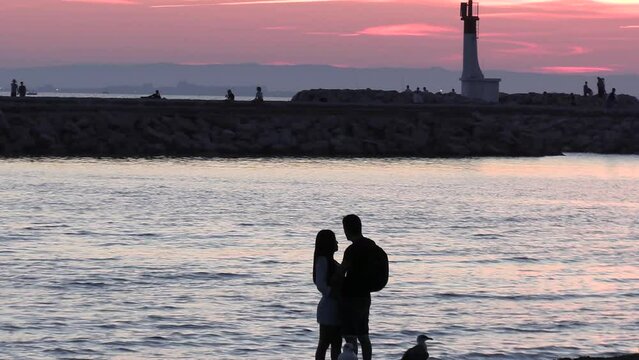 couple d'amoureux devant un d'un coucher de soleil sur la plage du grau du roi (Occitanie, France)