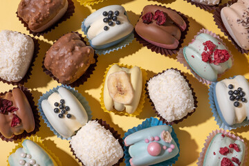 Set of different macaroons close up on yellow background top view, flat lay. Luxury delicious food aesthetics.