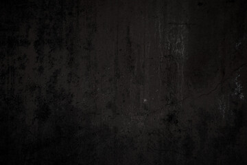 Front view of a dirty, worn and weathered dark gray concrete wall with paint partly faded. Abstract full frame textured background in black and white with copy space.