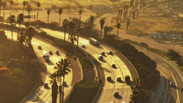 High angle view of rush hour on highway at sunrise. Vehicles passing through sharp turn on multilane thoroughfare. Ventura, California, USA