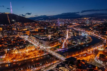 Fotobehang Panoramic night aerial view of Tbilisi, capital of Georgia from drone © Mulderphoto