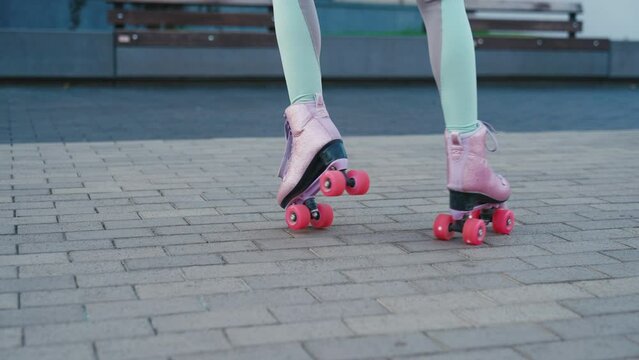Close up shot of young woman riding quad rollers skates in city. Happy riding retro rollerskates