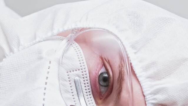 Vertical video. Medical scientist. Covid-19 outbreak. Female doctor woman in white protective equipment face mask glasses goggles coverall hood.