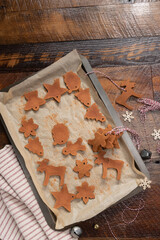 Cinnamon dough.  Parchment paper covered baking sheet with cinnamon dough ornament shape cut outs.  Star, Santa, Angel, snowflake, gingerbread person. 