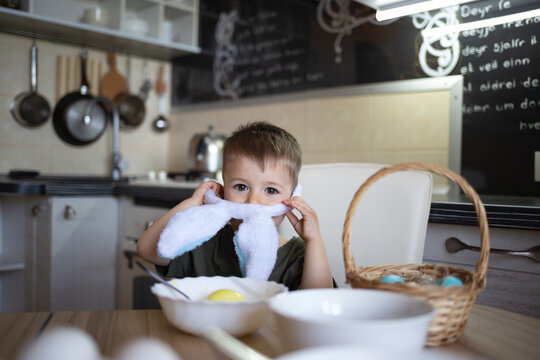 little cute boy paints eggs for easter sitting in the kitchen at the table