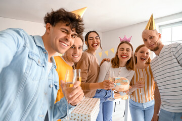 Group of young friends with Birthday cake taking selfie in kitchen