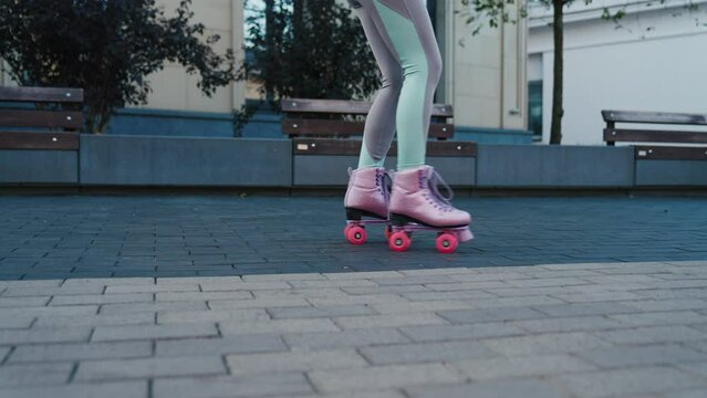 Close up shot of young woman riding quad rollers skates in city. Happy riding retro rollerskates