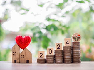 Wooden block with 2024 and goal business icon, miniature house on stack of coins. The concept of Property investment, House mortgage, Real estste.