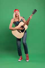 Happy hippie woman playing guitar on green background