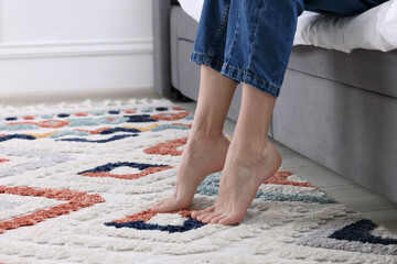 Woman on carpet with pattern at home, closeup. Space for text