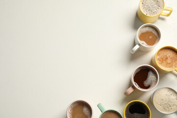 Many cups with different aromatic coffee on white table, flat lay. Space for text