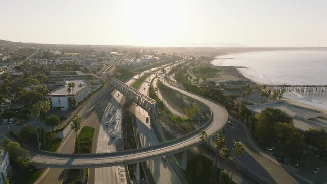 Aerial footage of multilevel road intersection and railway bridge in city. Morning shot at sunrise. Ventura, California, USA