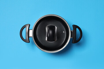 Empty pot with glass lid on light blue background, top view
