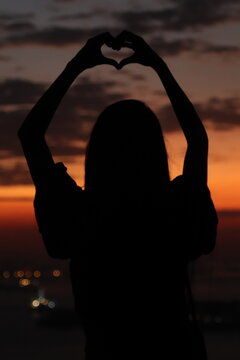 Silhueta De Uma Linda Mulher No Pôr Do Sol Alaranjado Com A Cidade Ao Fundo