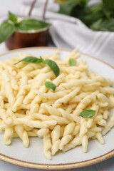 Plate of delicious trofie pasta with basil leaves on table, closeup