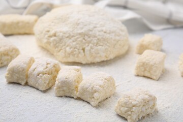Fototapeta na wymiar Making lazy dumplings. Raw dough and flour on white tiled table, closeup
