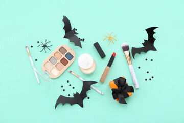 Makeup products and Halloween decor on turquoise background