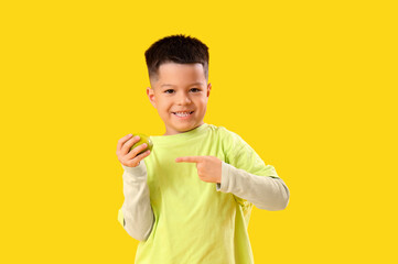 Little Asian boy pointing at fresh lime on yellow background