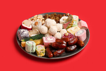 Plate with different tasty treats on red background. Divaly celebration