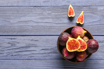 Bowl with ripe fresh figs on blue wooden background