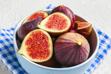 Bowl with ripe fresh figs on textured white background