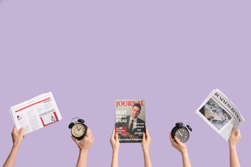 Hands holding alarm clocks, newspapers and magazine on lilac background