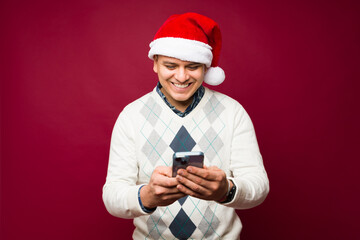 Hispanic man texting on the phone celebrating christmas