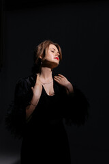 Studio portrait of a 30-year-old Caucasian woman in an avant-garde black dress. This image evokes...