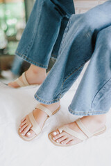 Slender beautiful female legs wearing beige shoes in studio. Street style, summer fashion trend, footwear, sandals, fashionable accessories, perfect skin, noface.