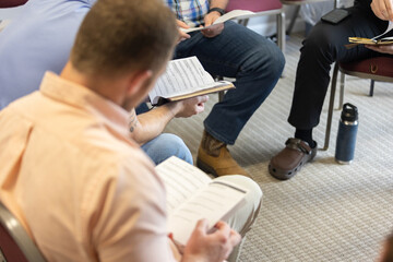 Selective focus on discussion questions in man's hands during men's Bible study during Sunday...