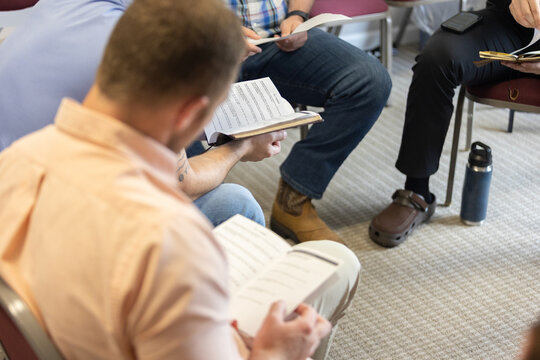 Selective focus on discussion questions in man's hands during men's Bible study during Sunday school at church, young men, young adults, young professionals