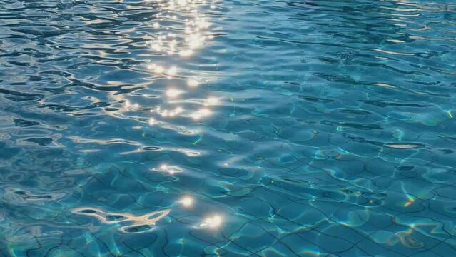 sun glare on the water of the pool - water abstract background. Surface of blue swimming pool. Background of blue ripped water in swimming pool