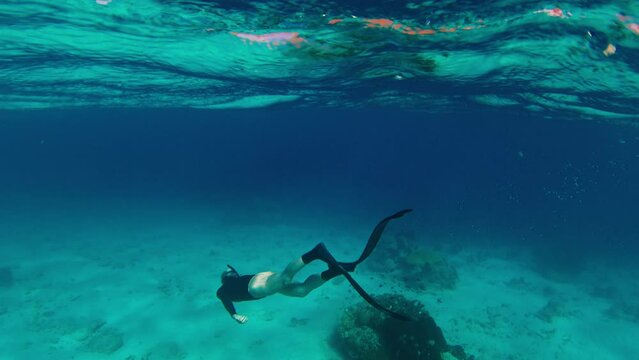 Freediver glides underwater over the sandy bottom in the Komodo National Park in Indonesia