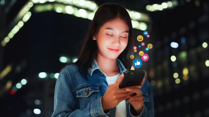 Young asian women watching live streaming video in the night city. Happy female using mobile...