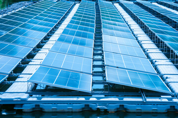 Side view of solar panels floating on water in a lake, for generating electricity from sunlight, selective focus, soft focus.