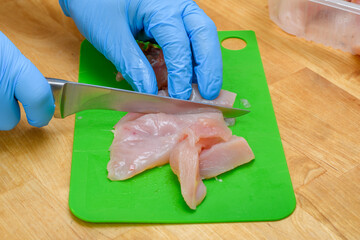 Kroić surowe mięso drobiowe na plastikowej desce do krojenia 