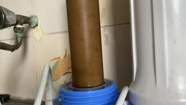 Turning white cover. Dirty water purifier micro filter 0.3 micron close up view at home on kitchen sink. Health and well being concept