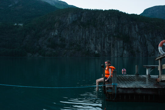 girl sat on a dock waiting to swim in a Norwegian Fjord