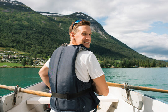 man happily rowing a boat in a Norwegian Fjord