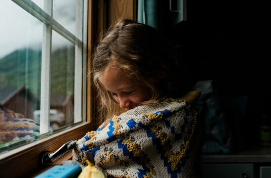 girl in a cosy norwegian jumper looking out the window of a cabin