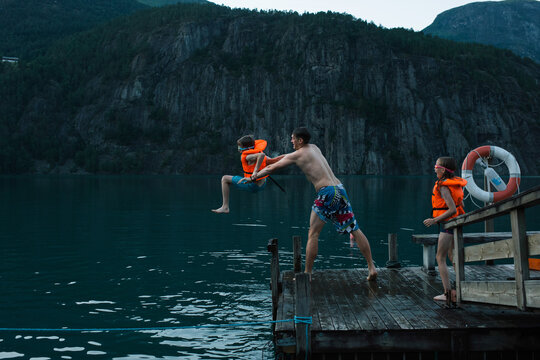 father playfully throwing his son into a Norwegian lake